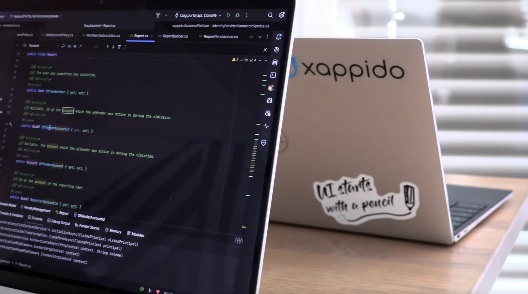 Laptop mit geöffnetem Code am Arbeitsplatz, daneben ein xappido-Aufkleber