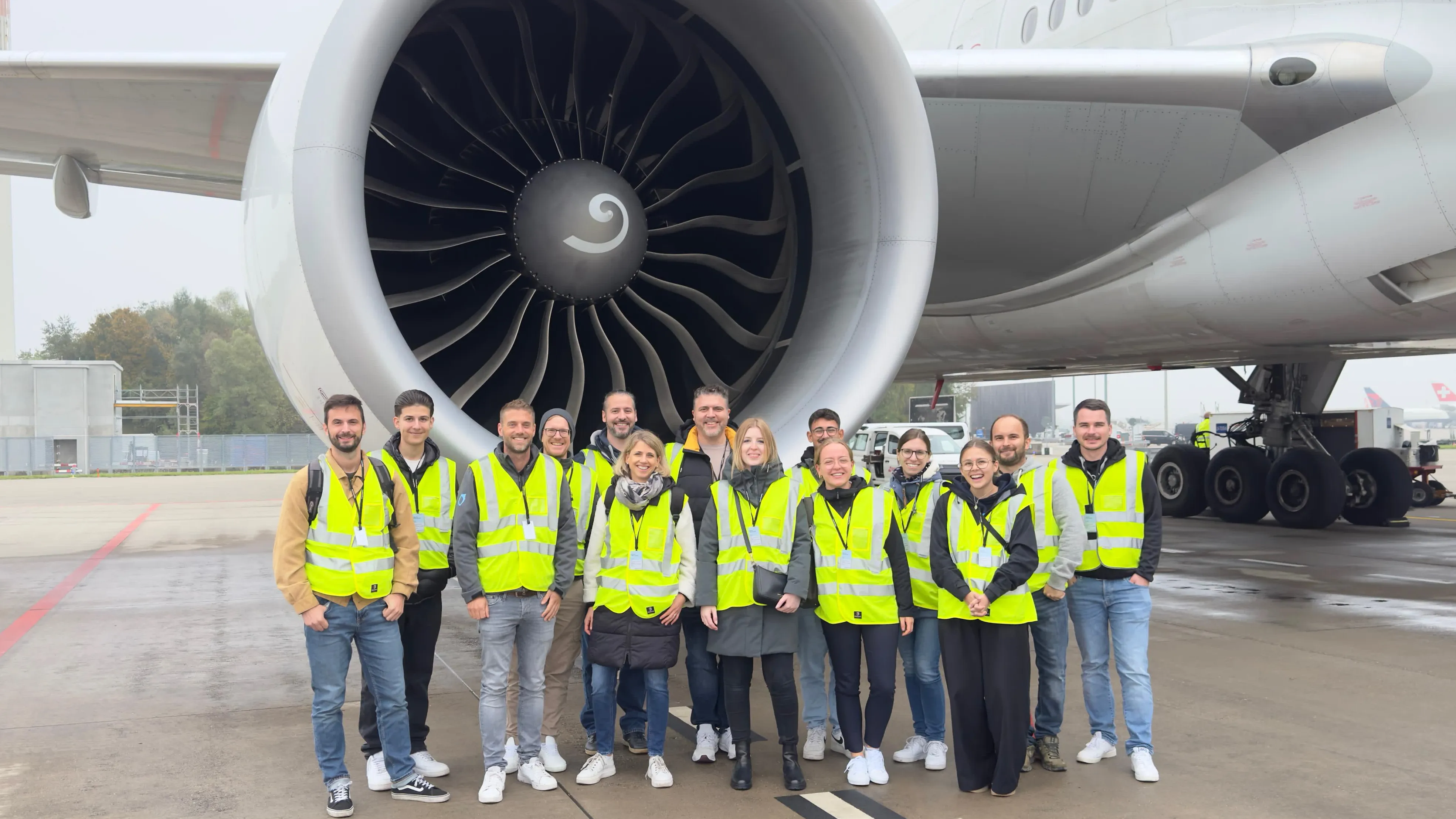 Das Team in Warnwesten vor einem Flugzeugtriebwerk